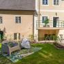 Old post office garden with seating, © Aumüller Caroline Garden with seating in front of an old building with a yellow façade and green window frames.