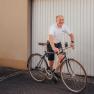 Bike garage, service, rental, tours, © Niederösterreich Werbung/Daniela Führer Man in white polo shirt riding bicycle in front of garage door.