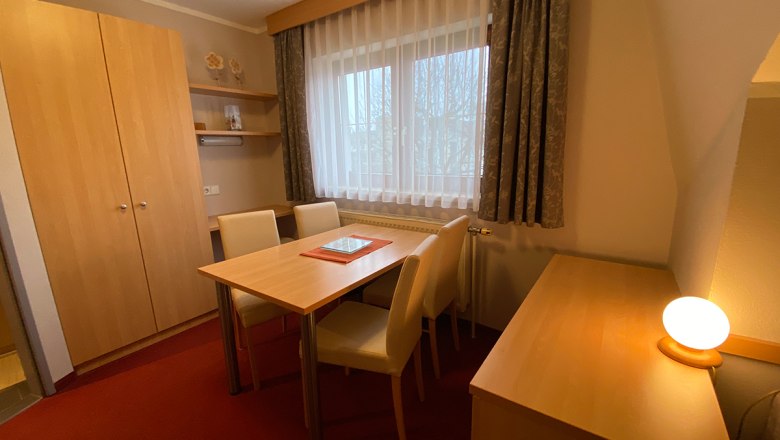 Vacation apartment Herbst, © Privatzimmer Leeb A cozy room with wooden furniture, table, chairs and a window with curtains.