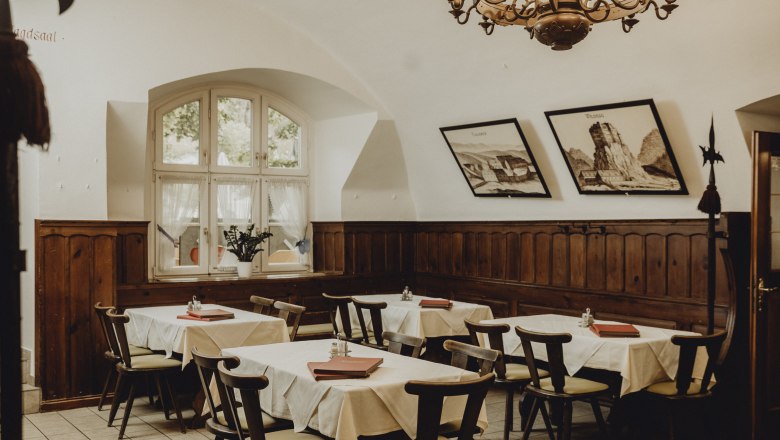 Unique ambience, © Niederösterreich Werbung/Sophie Menegaldo Cozy dining room with wooden furniture, white tablecloths and murals.