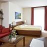 Country inn 'Zur Schönen Wienerin', © Engel Cozy hotel room with double bed, red sofa, glass table and decorations.