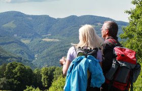 Municipality of Lilienfeld, © weinfranz.at Two hikers with rucksacks look out over a mountainous landscape.