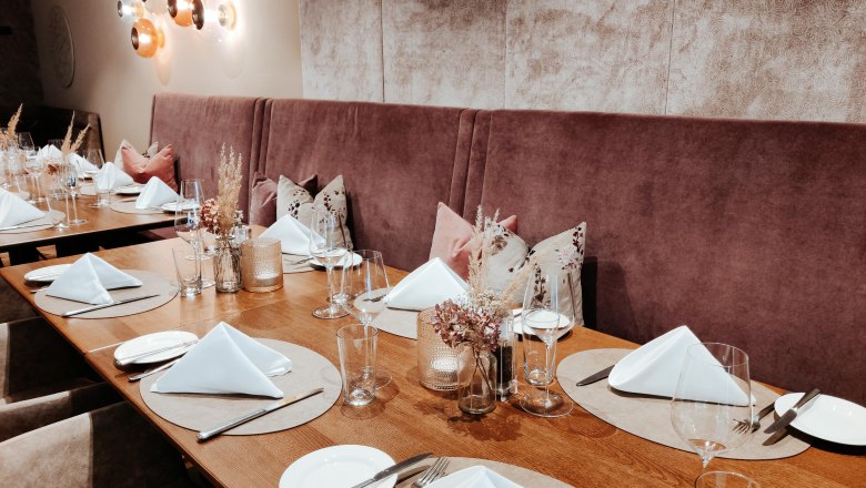 Restaurant Wintergarten Table set, © Hotel Schachner_miku Media An elegantly laid table in a restaurant with white napkins, glasses and cutlery on a wooden surface.