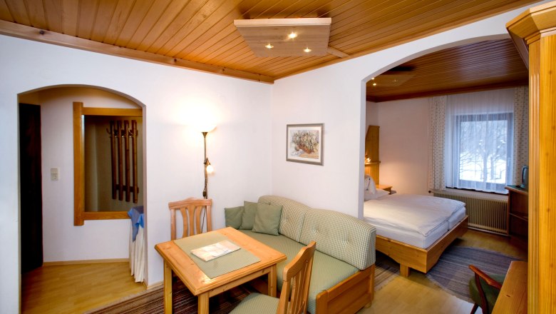 Room Gamsblick, © Pension Landhaus Ingrid Comfortable hotel room with wooden furniture, dining table, sofa and double bed.