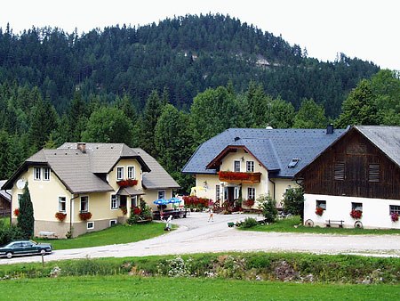 Wood yard, © Holzhof Three houses in a rural setting with a forest in the background.