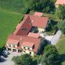 Vacation apartments & private rooms Leeb, © Privatzimmer Leeb Aerial view of a large house with red roofs, surrounded by green fields and trees.