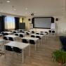 Seminar room, © Wiener Alpen An empty seminar room with white tables, black chairs and a large screen at the front.