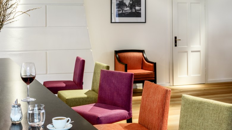 Hotel zum Glockenturm, © croce&wir Interior view of a modern hotel lounge with colorful chairs, a table with drinks and a picture on the wall.