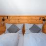 Leopold an der Ybbs, © © Niederösterreich Werbung/ Maximilian Pawlikowsky Comfortable double bed with wooden back panel, gray cushions and blankets. A retro radio on the left, a reading lamp and heart decoration on the right.