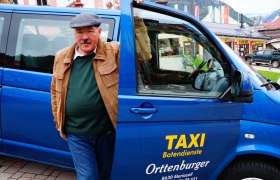 Cab Orttenburger, © Ernst Miglbauer A man is standing next to a blue cab with the sign 'Taxi Botendienste Orttenburger'.