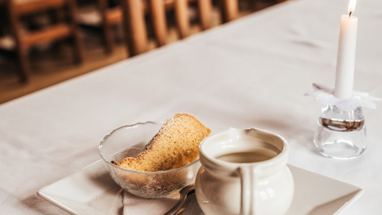 Mostschober, © Niederösterreich Werbung/Daniela Führer A laid table with a plate, a cup, a piece of cake and a lit candle.
