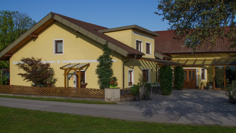 House view, © Privatzimmer Leeb Yellow detached house with red roof and garden.