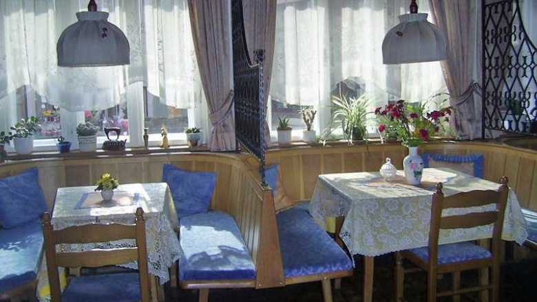 Bed and breakfast family Loidhold, © Familie Loidhold Cozy breakfast room with wooden furniture and blue upholstery, decorated with plants and flowers.