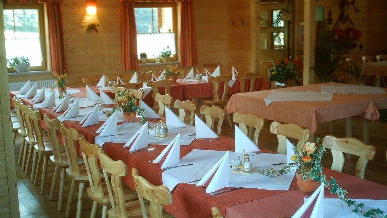 Gasthof am Holzschlag, © zVg Gasthof am Holzschlag A rustic dining room with wooden furniture, laid tables and decorative flower arrangements.