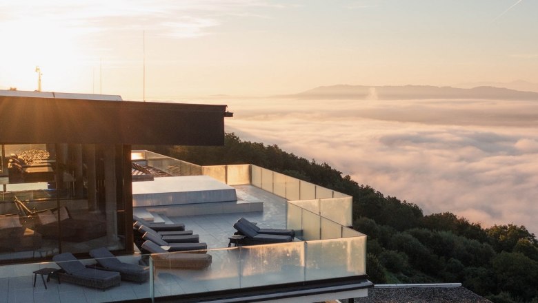 Hotel Schachner outdoor pool with misty ceiling, © Hotel Schachner_MIKU Media Modern building with terrace above a sea of fog at sunrise.