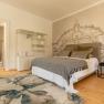 Example sleeping area, © Guestia GmbH A stylishly furnished bedroom with a large bed, decorative cushions, a rug and an artistic wall design.