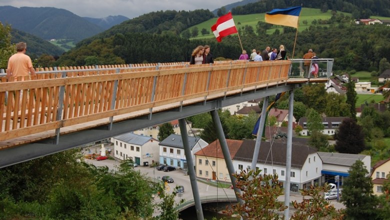 Viewing platform opening, © Gerhard Hackner People on a wooden platform with Austrian and Ukrainian flags, a rural landscape in the background.