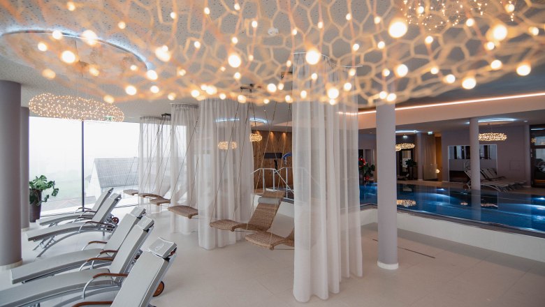 Relaxation area in the WACHAUF Spa, © Hotel Schachner_MIKU Media Modern spa relaxation area with loungers, hanging chairs and pool.