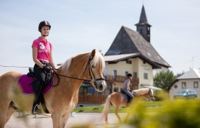 Riding lessons are also offered at the Schaglhof, © Fred Lindmoser Two female riders on horses in front of a building with a tower.