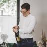 Andreas Graf manages the family-run restaurant with zeitgeist and vision, © Niederösterreich-Werbung/David Schreiber A man opens a bottle of wine at a table set with food.