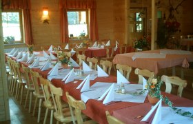 Gasthof am Holzschlag, © zVg Gasthof am Holzschlag A rustic dining room with wooden furniture, laid tables and decorative flower arrangements.