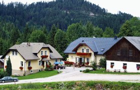 Wood yard, © Holzhof Three houses in a rural setting with a forest in the background.