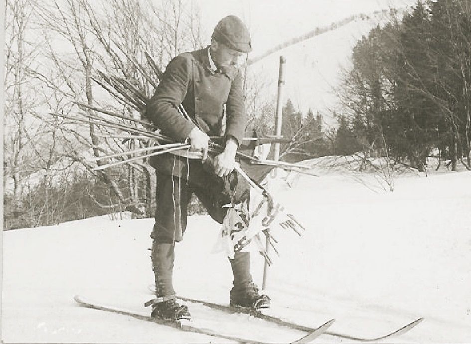 Historical photograph of a man on skis with ski poles in the snow.