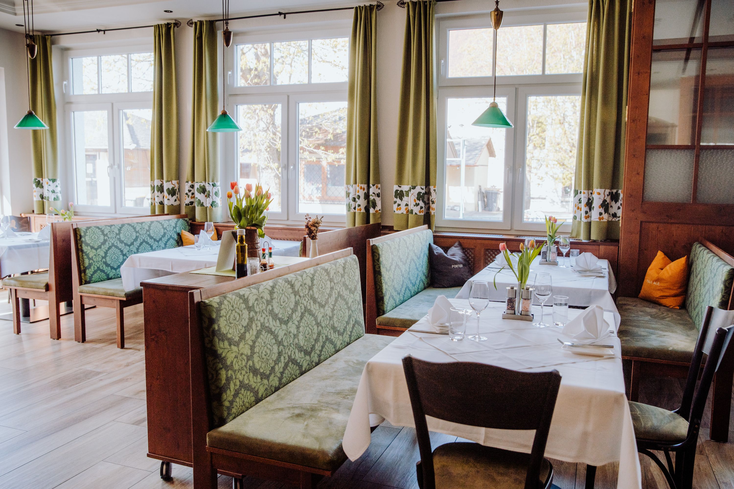 Cozy restaurant with green benches and table decorations.
