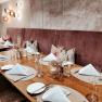 An elegantly laid table in a restaurant with white napkins, glasses and cutlery on a wooden surface.