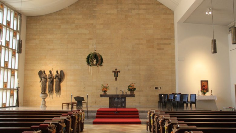 Interior view of a church with altar, pews and religious sculptures.