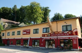 Exterior view of a bakery with yellow facade and red sign.