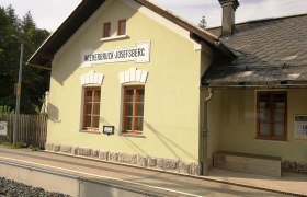 Wienerbruck-Josefsberg station building with yellow fa&ccedil;ade and slate roof.