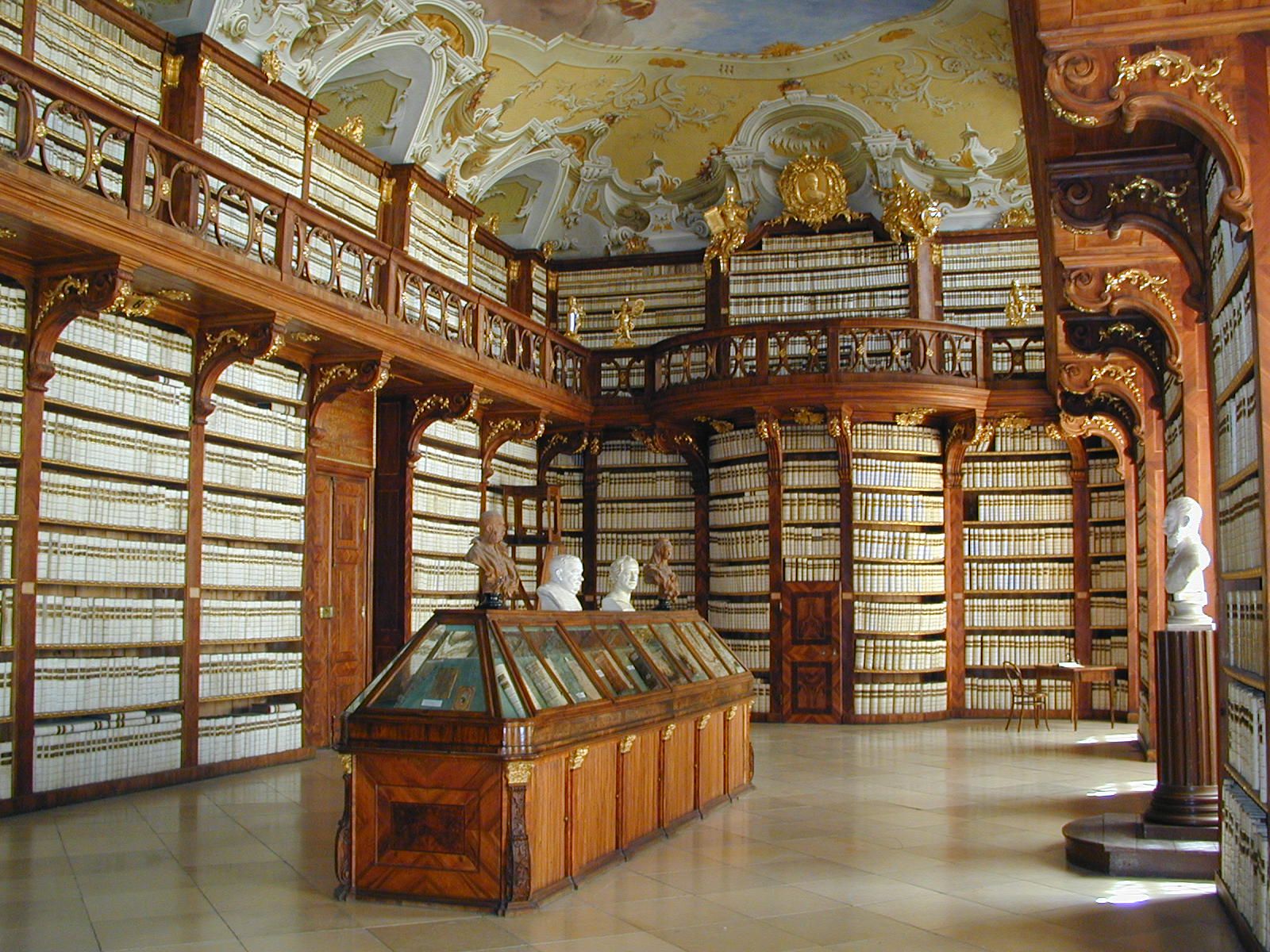 Interior view of the library in Seitenstetten Abbey with richly decorated wooden shelves and busts.