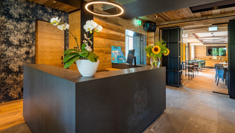 Modern reception with wood paneling, orchids and sunflowers on the counter.