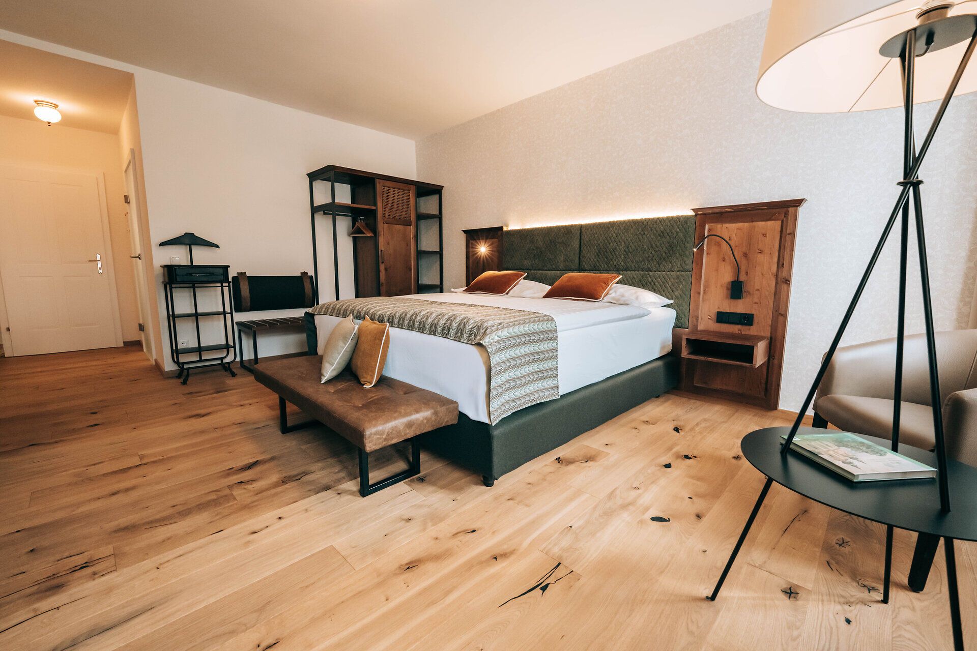 Modern hotel room with double bed, wooden floor and stylish furniture.