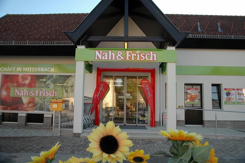 Entrance to a Nah & Frisch supermarket with sunflowers in the foreground.