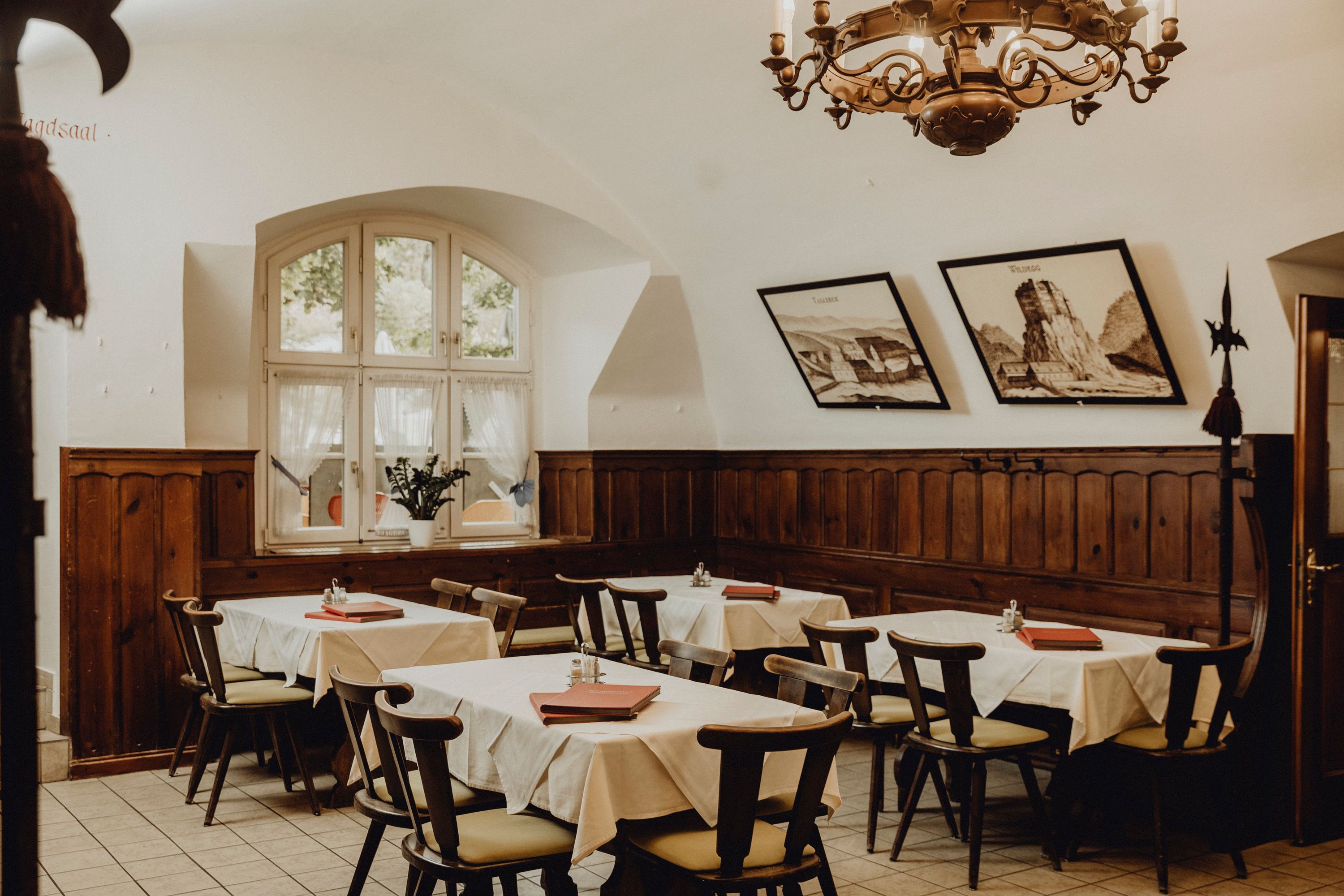 Cozy dining room with wooden furniture, white tablecloths and murals.