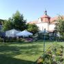 Garden with flower beds, white tents and historic building in the background.