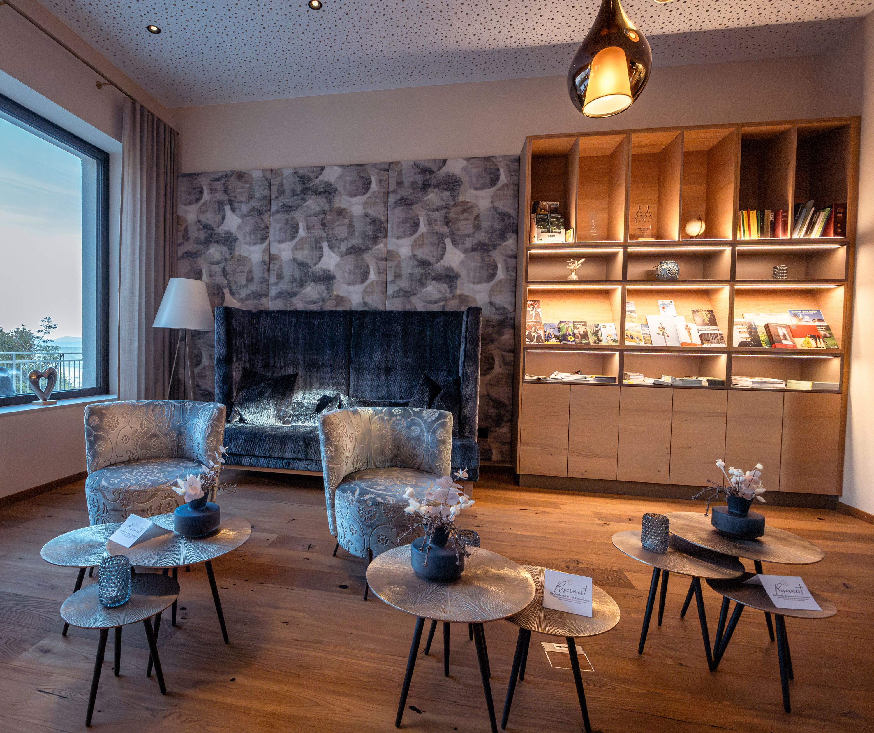 Cozy hotel lounge area with armchairs, coffee tables and bookshelf.