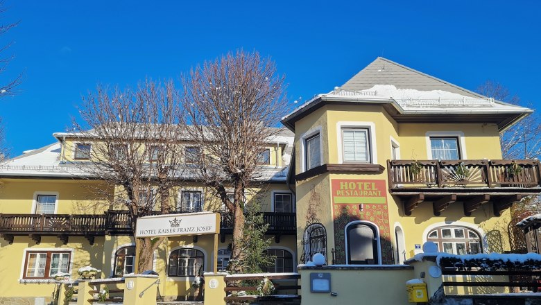 Yellow hotel building with wooden decorations and blue sky in the background.