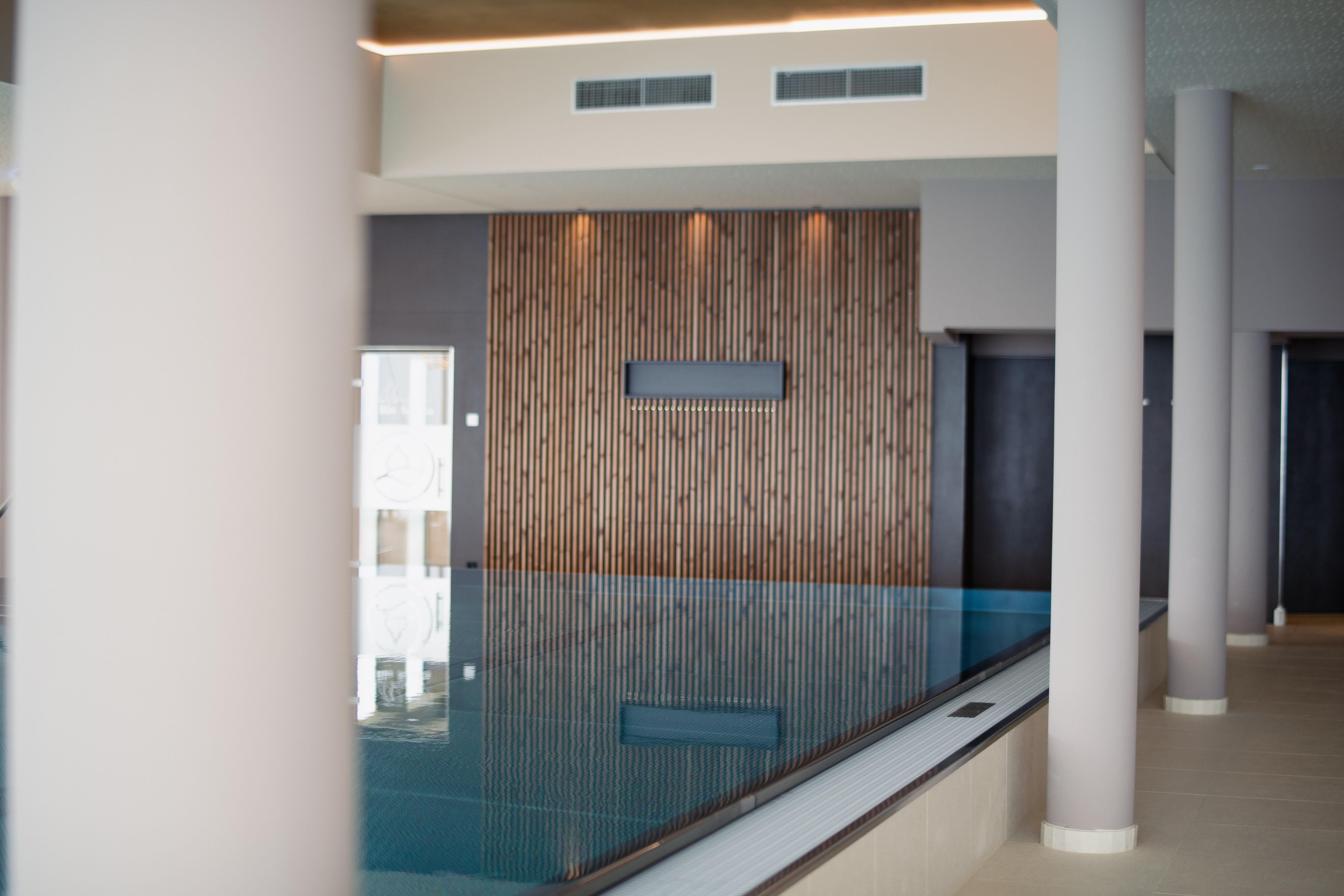 Interior view of an infinity pool at the Hotel Schachner with wooden cladding and modern columns.