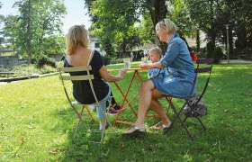 Three people sit at a table in the park of Rothschild Castle.