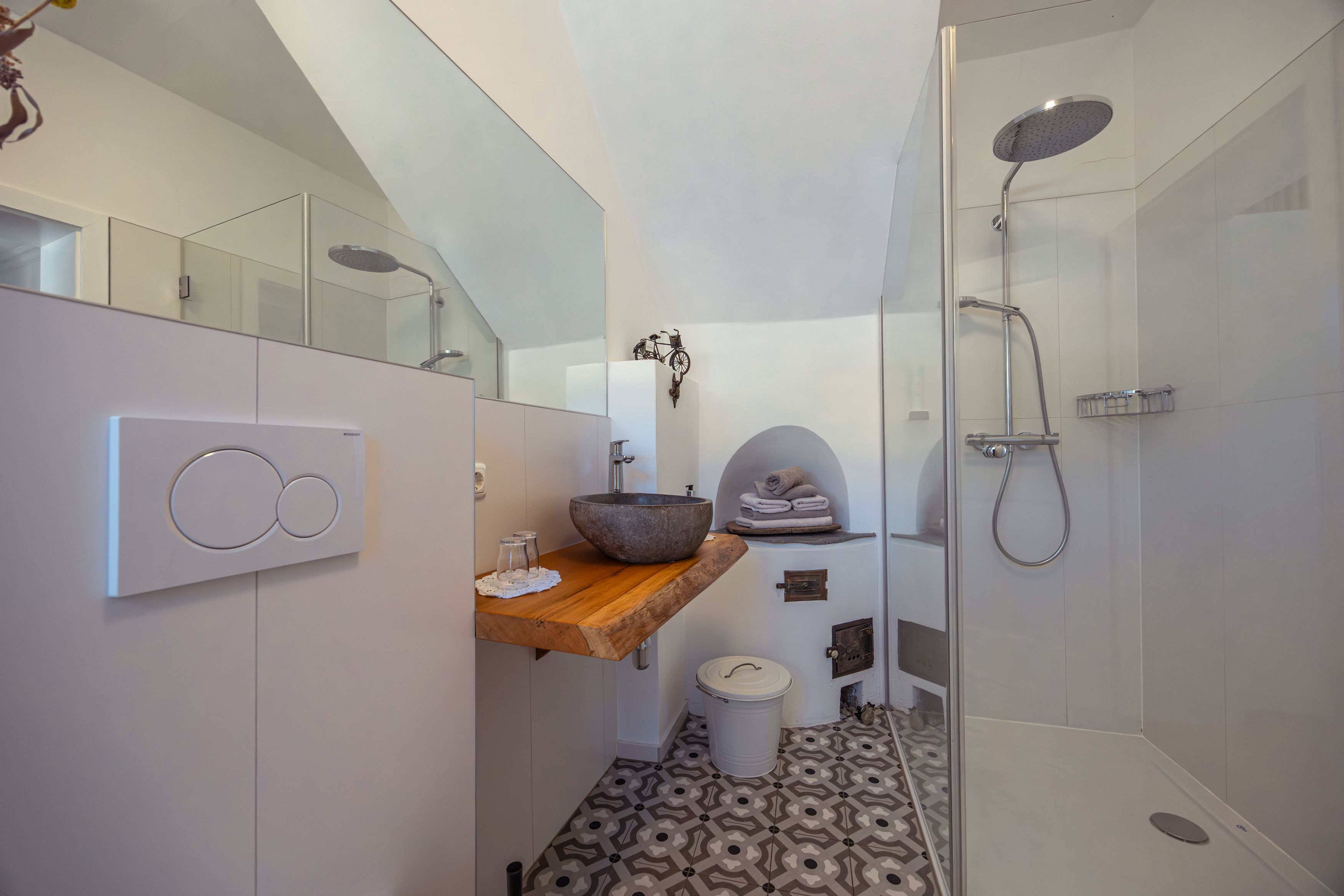 Modern bathroom with glass shower, stone washbasin and patterned floor.