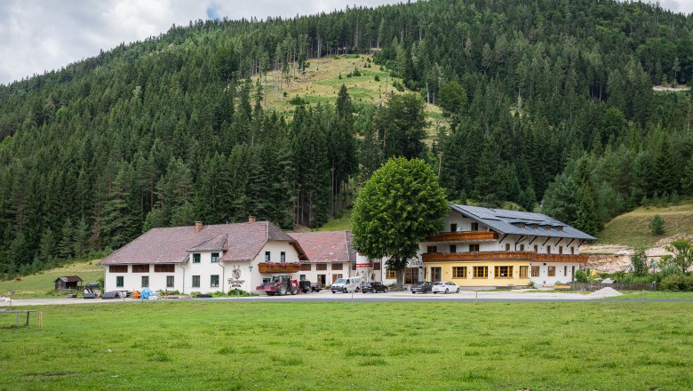 Gasthof Furtner in front of a wooded hill.