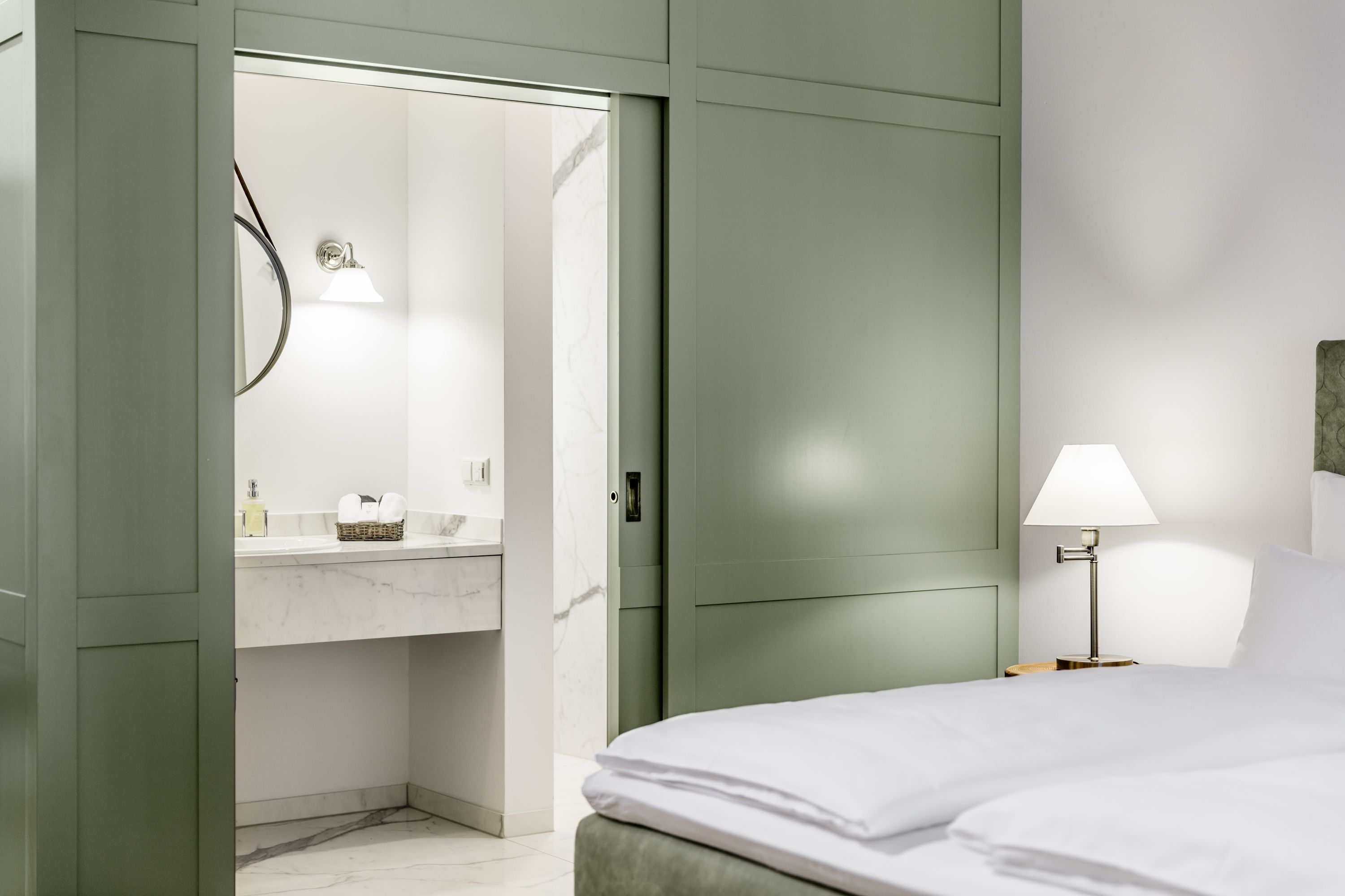 Hotel room with green sliding-door wardrobe, bed and view of the bathroom.