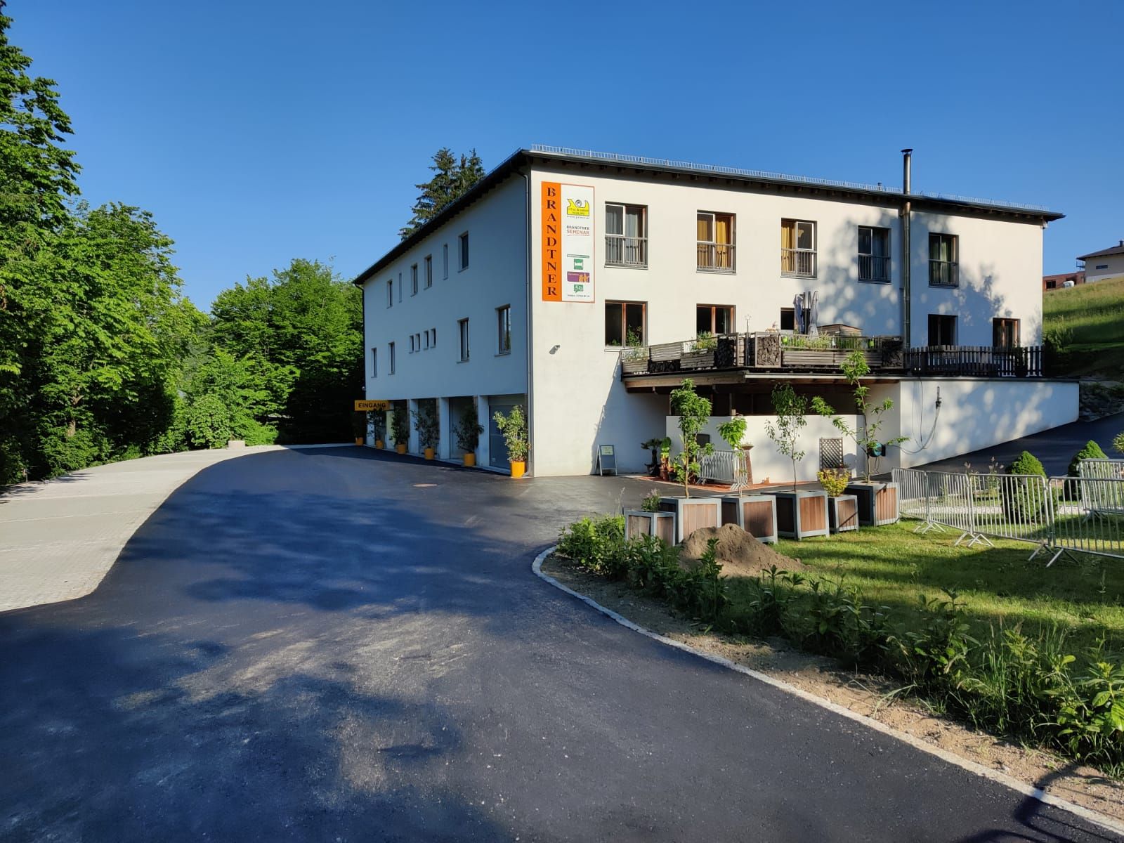 Building with the inscription 'Brandtner', surrounded by trees and a parking lot.