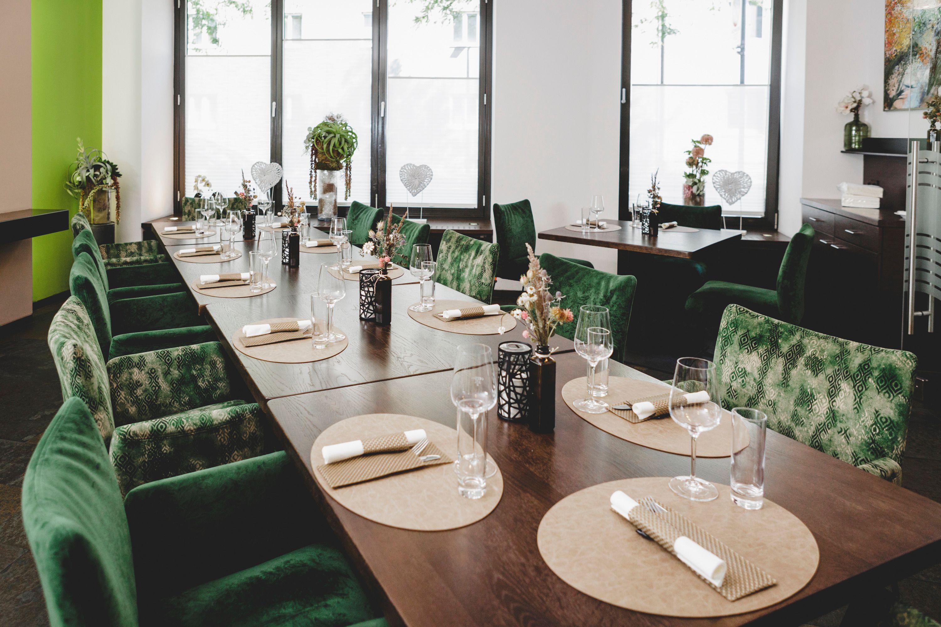 Elegant restaurant with green chairs and table setting.