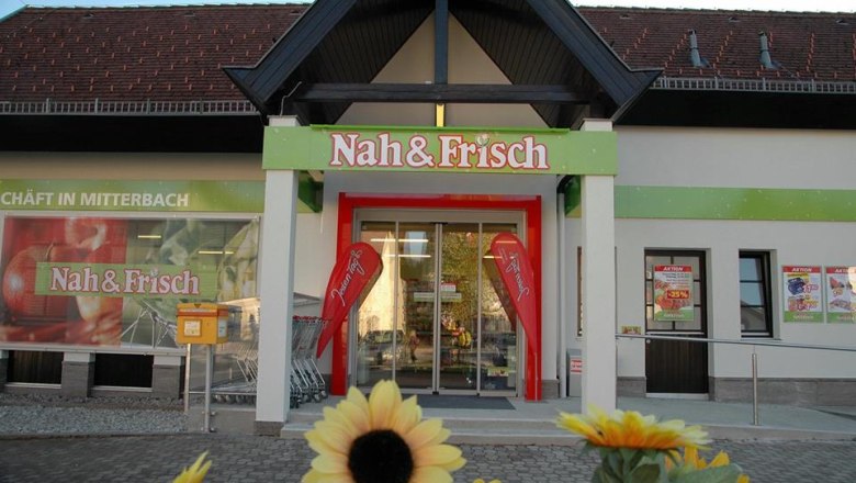 Entrance to a Nah & Frisch supermarket with sunflowers in the foreground.