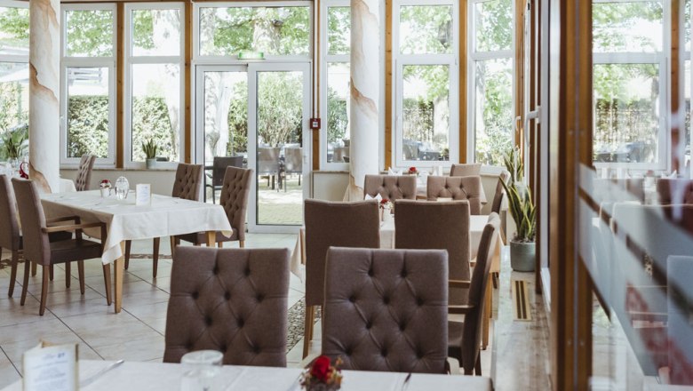 Interior view of an elegant restaurant with set tables and large windows.