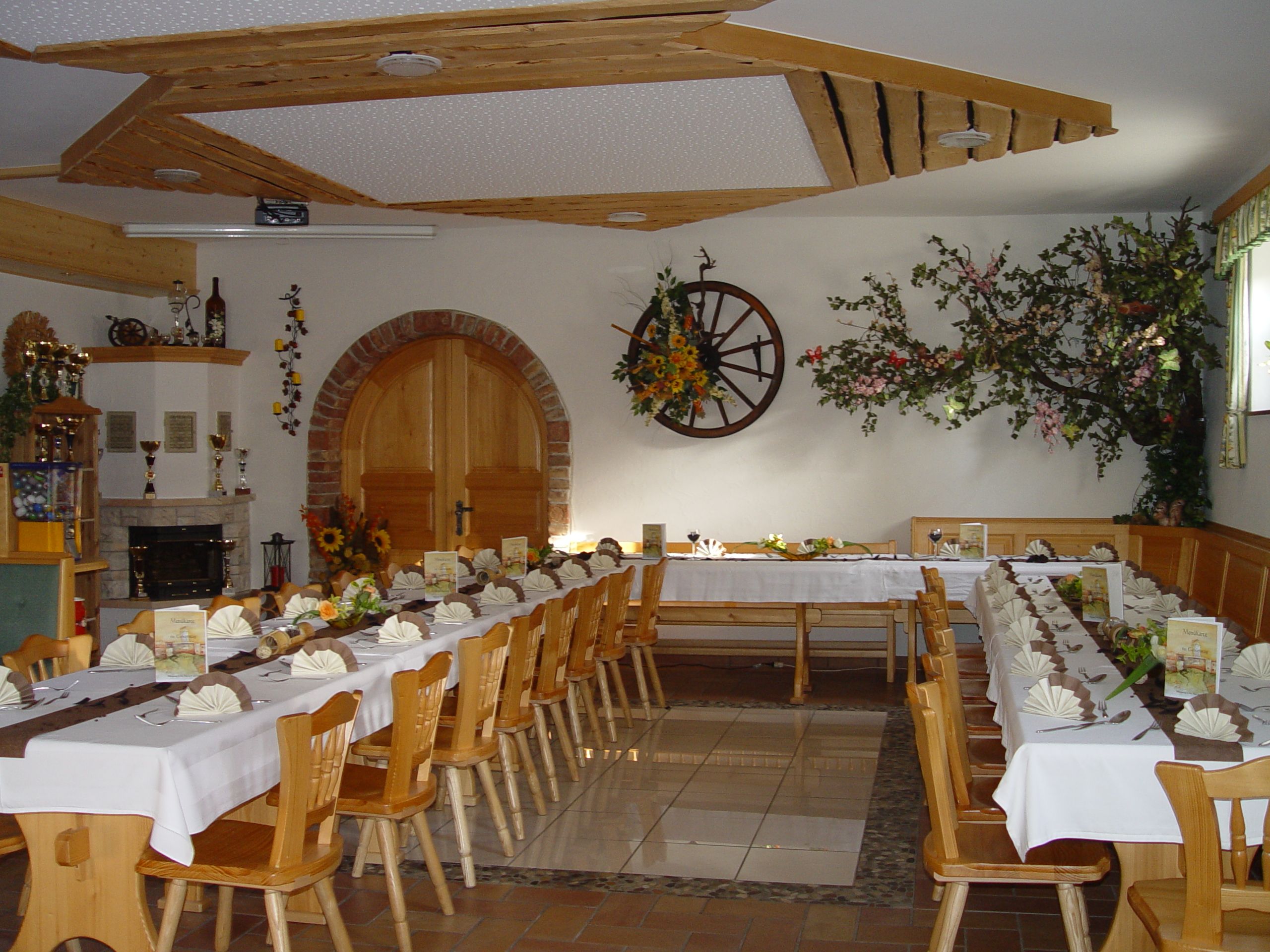 A festively decorated dining room with long tables, decorated with flowers and napkins, in a rustic ambience.